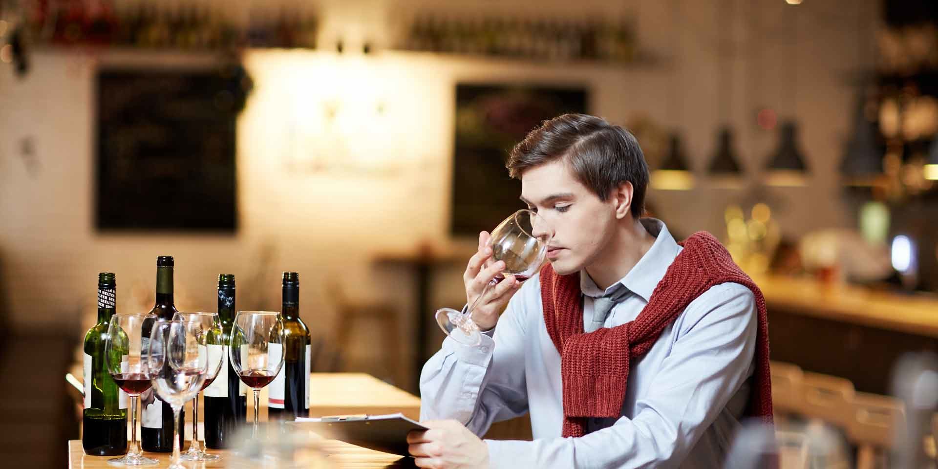 jeune homme degustant du vin rouge degustation oenologique